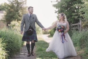 Bride and groom walking, holding hands looking at each other