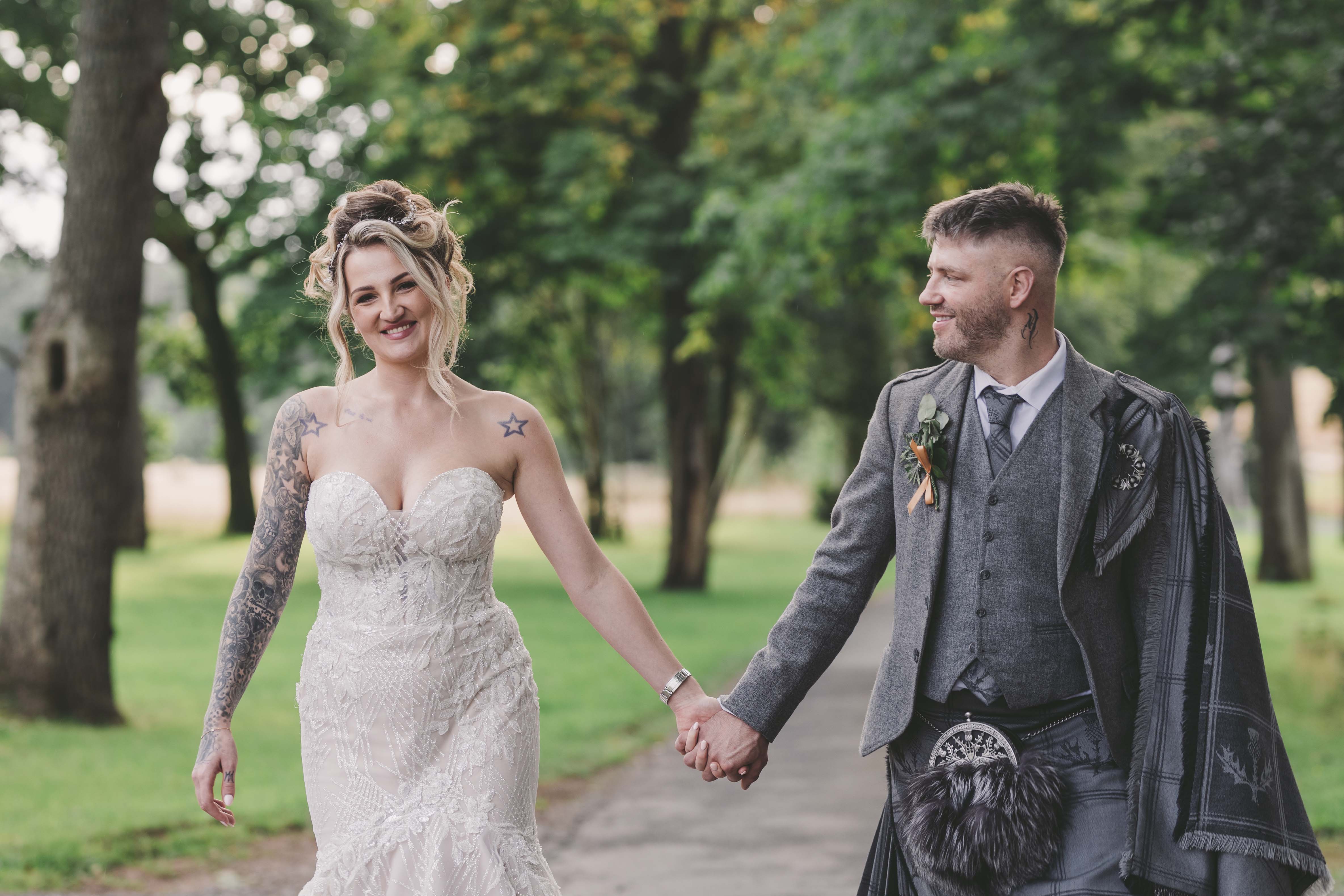 Bride and groom holding hands at Enterkine House hotel. Groom is looking at his new wife