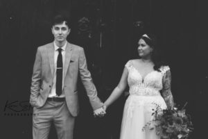 Black and white, bride and groom holding hands.