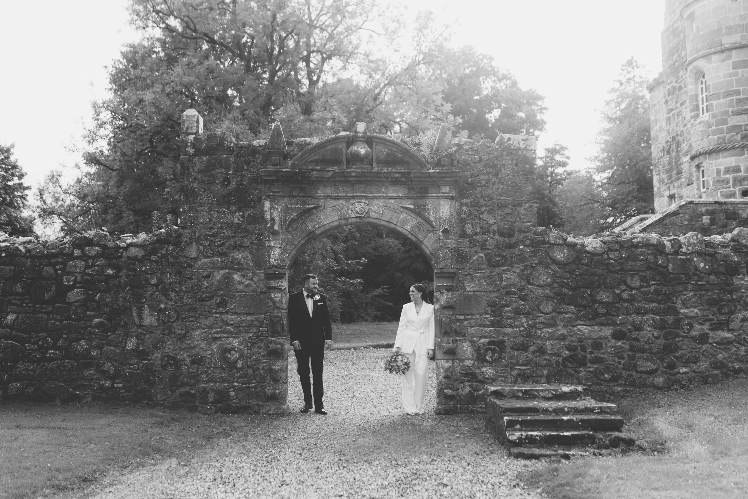 Bride in a white suit with groom in a tux at Rowallan Castle