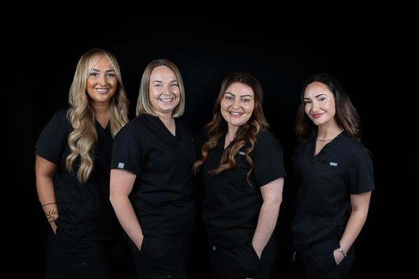 Four woman together for headshots wearing black scrubs